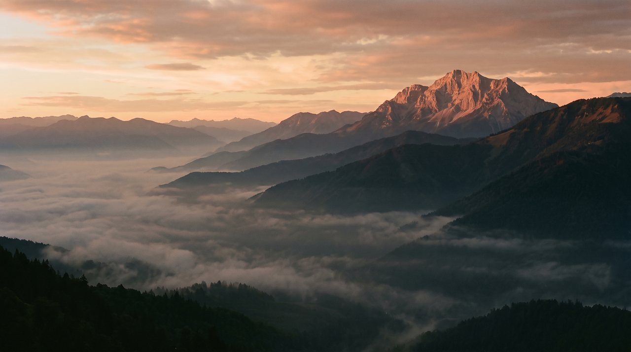 A mountain ridge rising above a sea of morning mist at dusk